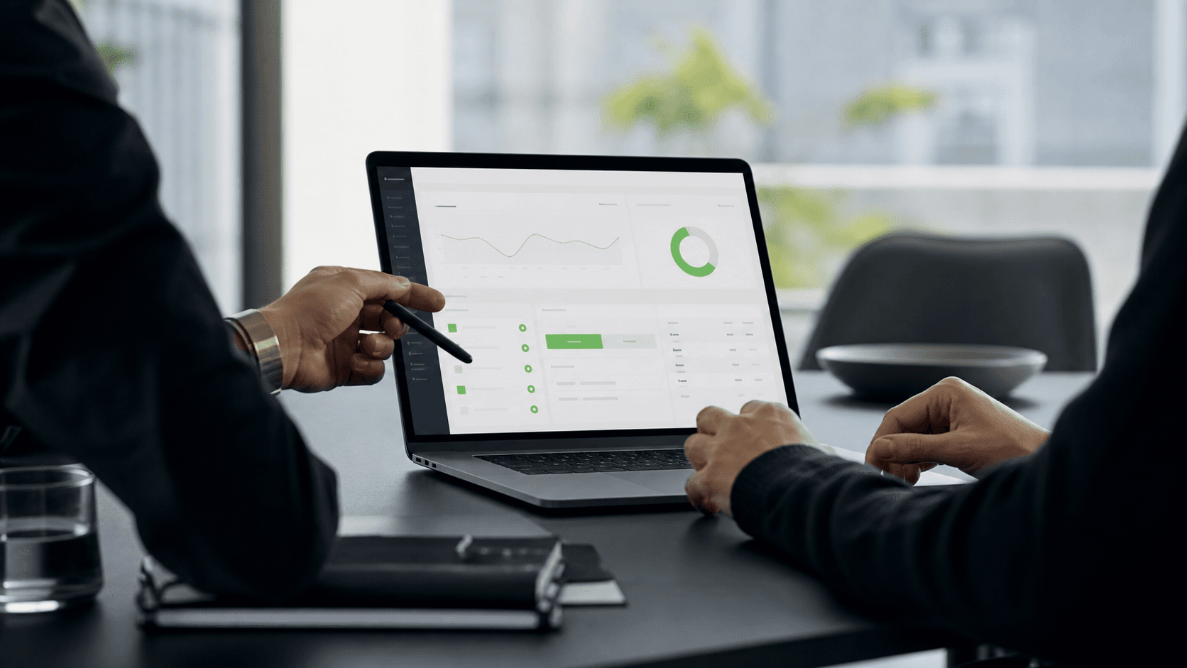 Two professionals reviewing a clean project dashboard on a laptop during a client meeting.